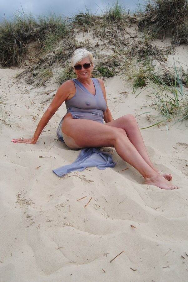 19P Die schöne vollbusige reife Dimonty posiert vollständig bekleidet in einem hauchdünnen Kleid am Strand