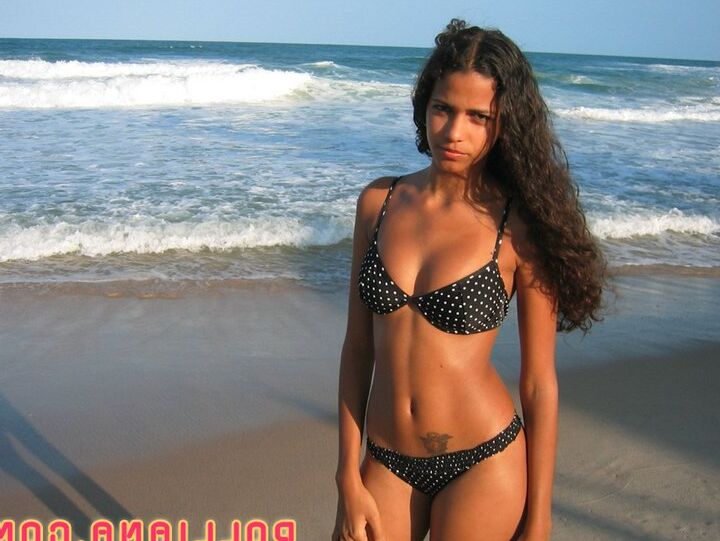 16P La amateur brasileña Polliana modela en bikini en una playa de arena