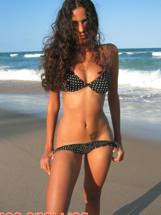 16P La amateur brasileña Polliana modela en bikini en una playa de arena
