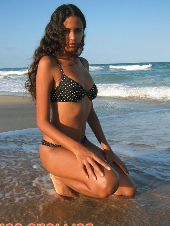 16P La amateur brasileña Polliana modela en bikini en una playa de arena