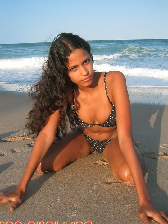 16P La amateur brasileña Polliana modela en bikini en una playa de arena