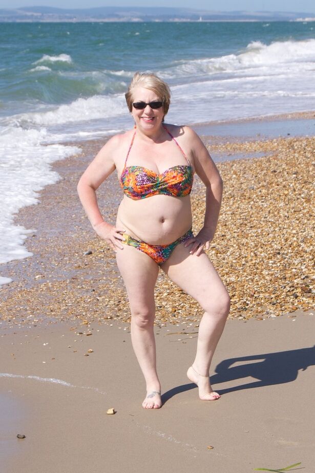 20P Mature UK woman Speedy Bee wears sunglasses while getting naked at the beach