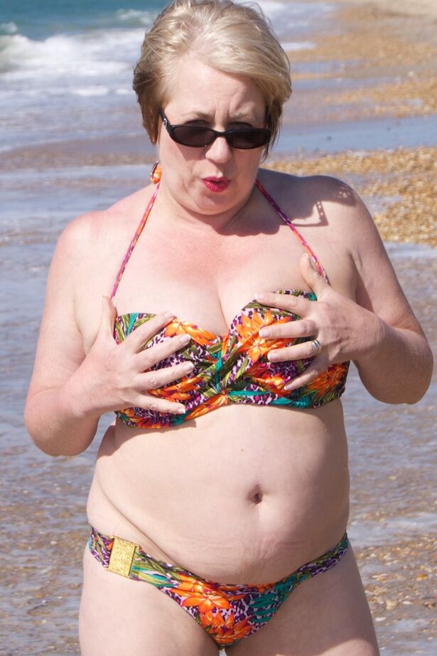20P Mature UK woman Speedy Bee wears sunglasses while getting naked at the beach
