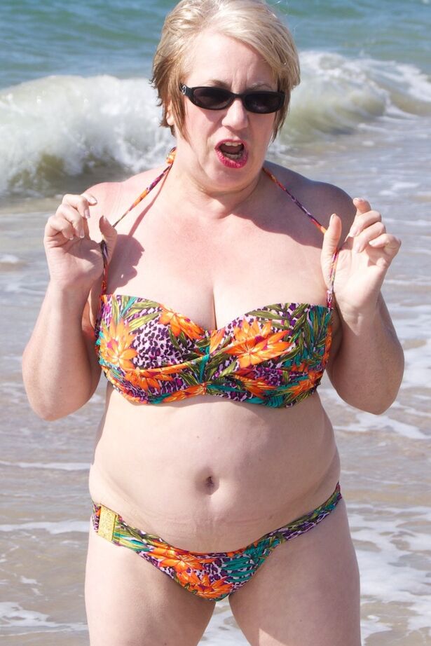 20P Mature UK woman Speedy Bee wears sunglasses while getting naked at the beach