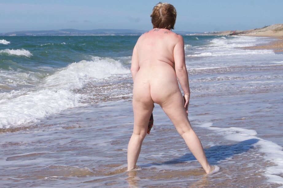 20P Mature UK woman Speedy Bee wears sunglasses while getting naked at the beach