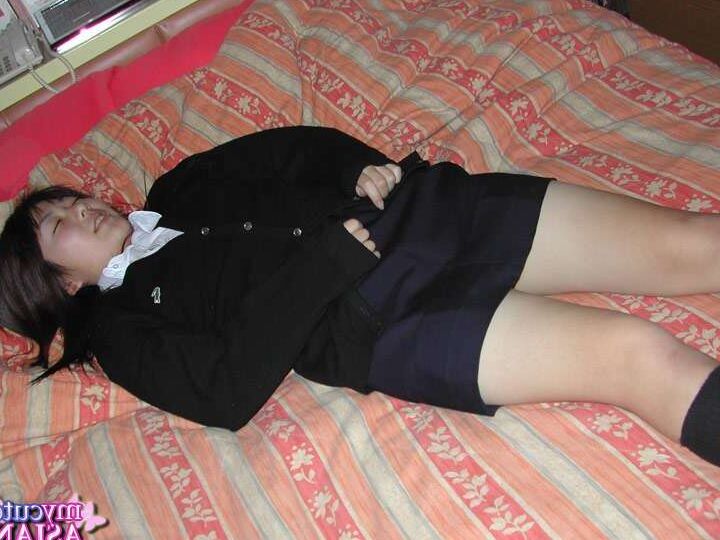 Eine 16-jährige junge Asiatin entblößt langsam ihre flache Brust und ihren gestutzten Busch auf ihrem Bett
