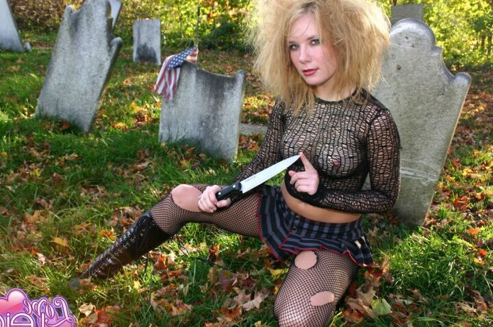 12P Amateurmodel leckt ein Messer, während es zerrissene Strümpfe auf einem Friedhof trägt
