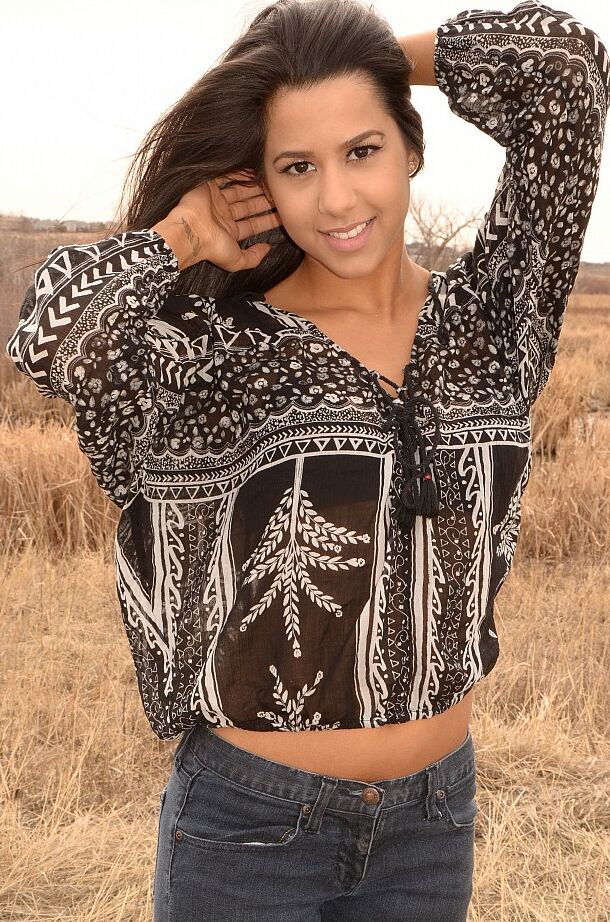 12P A garota latina Bella Quinn modela em um campo usando sutiã e jeans