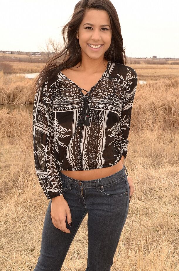 12P A garota latina Bella Quinn modela em um campo usando sutiã e jeans