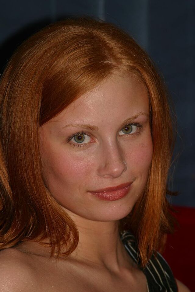 16P Anya, la rousse naturelle, enlève son string rouge pour se poser nue sur un canapé rouge