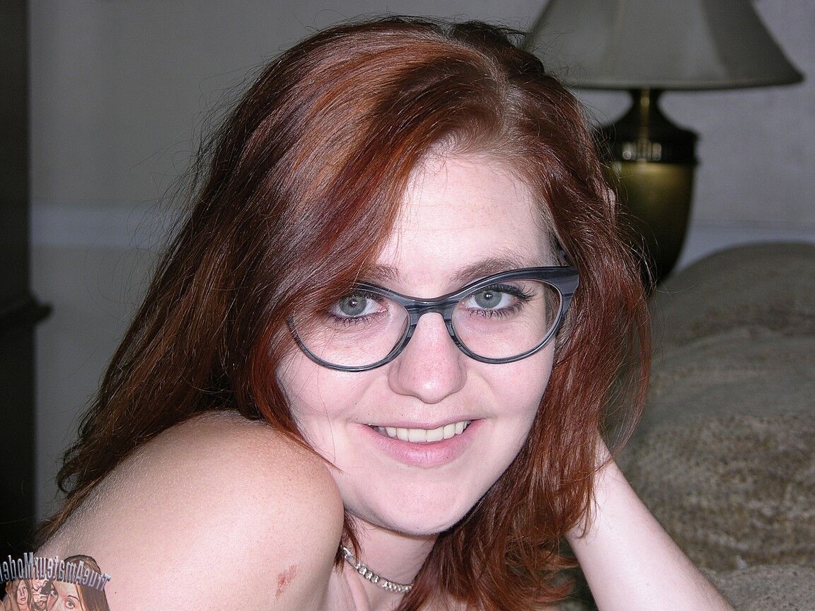 17P Young redhead with pierced nipples gets naked with her glasses on