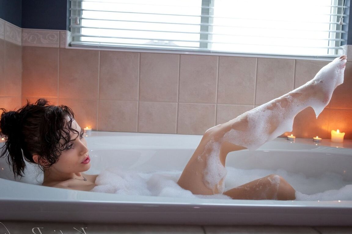 15P Katie Banks, amatrice brune, montre sa chatte rose dans une baignoire à la lueur d'une bougie.