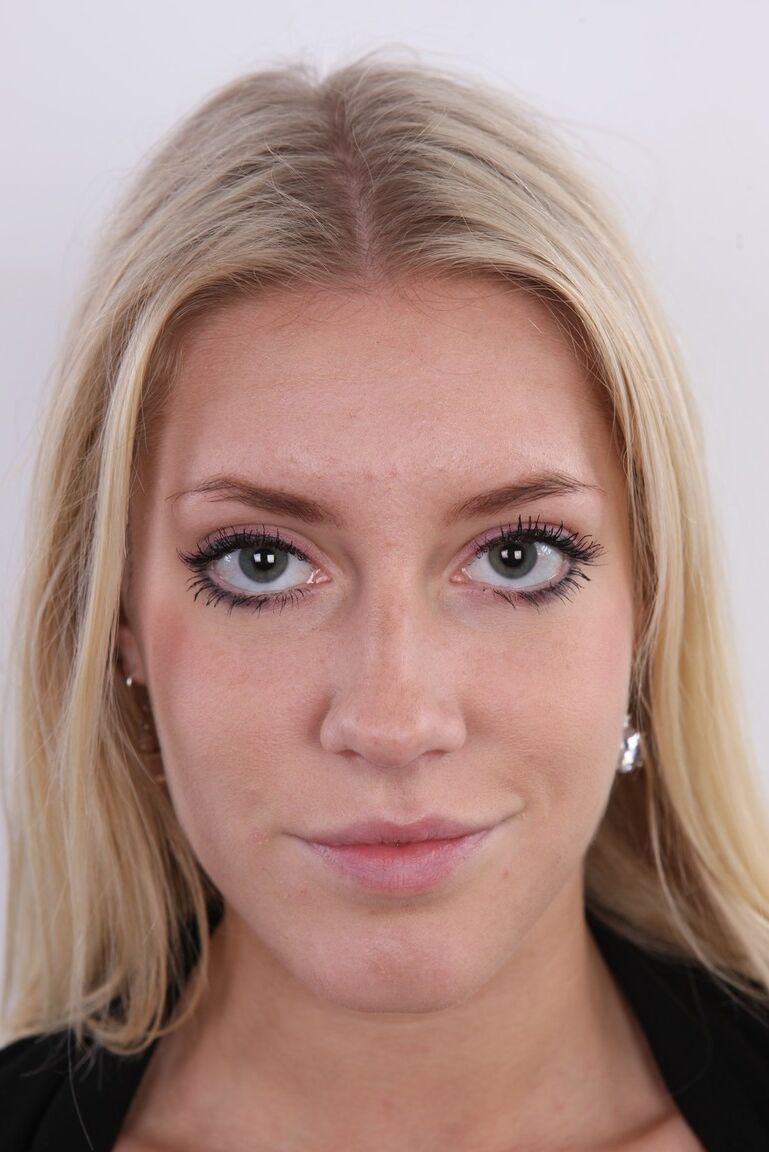 20P Blonde amateur Klara stands fully clothed and then totally naked afore a wall