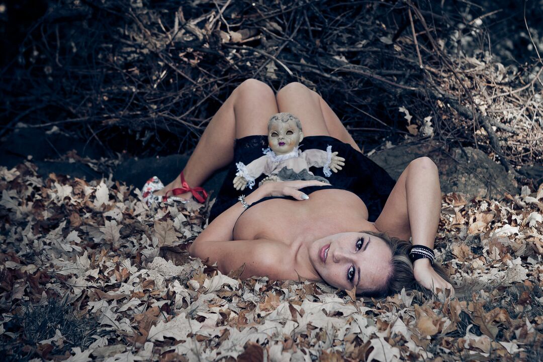 15P Amateur model Nikki Sims holds a creepy doll while squeezing her tits outside