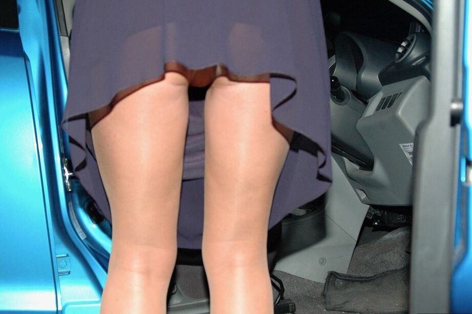 20P Kyra amadora mais velha desliza a mão pela meia-calça transparente à noite perto de um carro