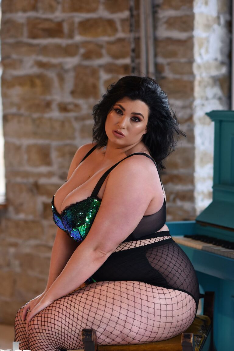 21P BBW babe Kiki poses in fishnets & strips to cradle her colossal breasts