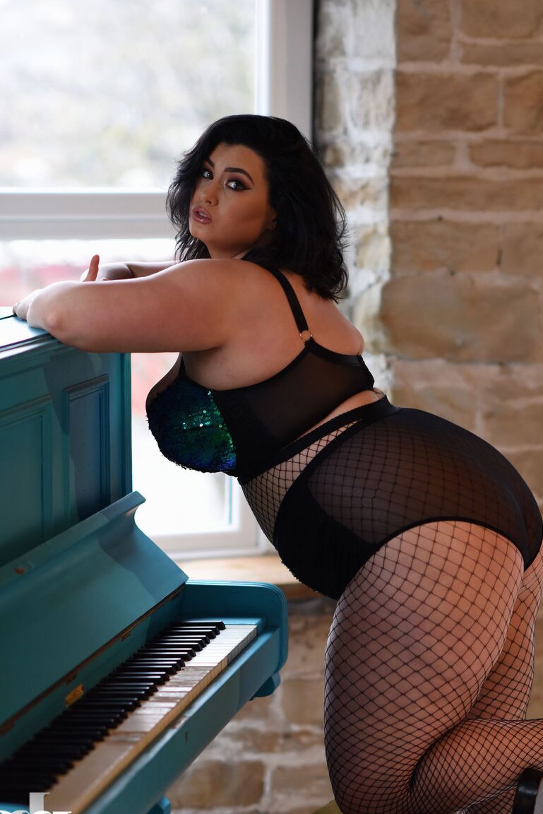21P BBW babe Kiki poses in fishnets & strips to cradle her colossal breasts