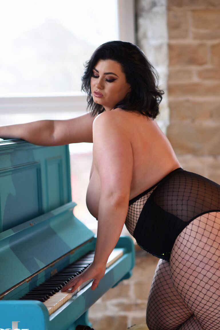 21P BBW babe Kiki poses in fishnets & strips to cradle her colossal breasts
