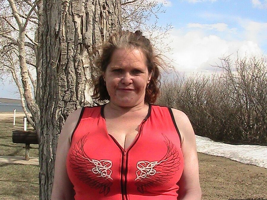 20P Older redhead Misha MILF displays her large tits by a lake before dildo riding