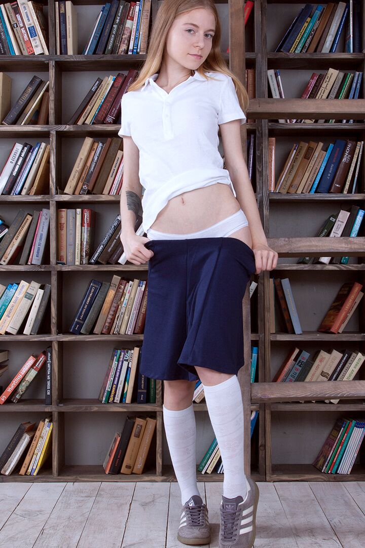 16P Adolescente delgada muestra su ropa interior de algodón mientras hojea libros en la biblioteca