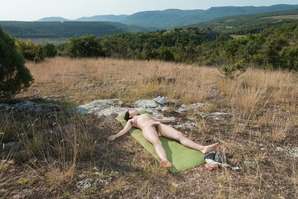 16P El amateur totalmente natural Ole Nina se recuesta sobre una estera de yoga bajo el cielo despejado en la cima de una colina