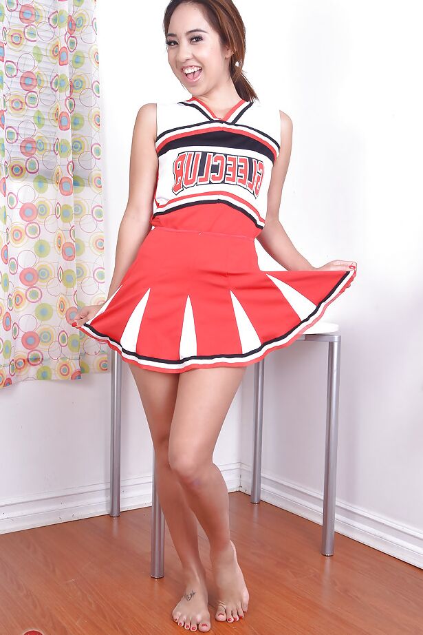 16P Mila Jade, jeune amatrice asiatique, expose ses petits seins sous une tenue de pom-pom girl.