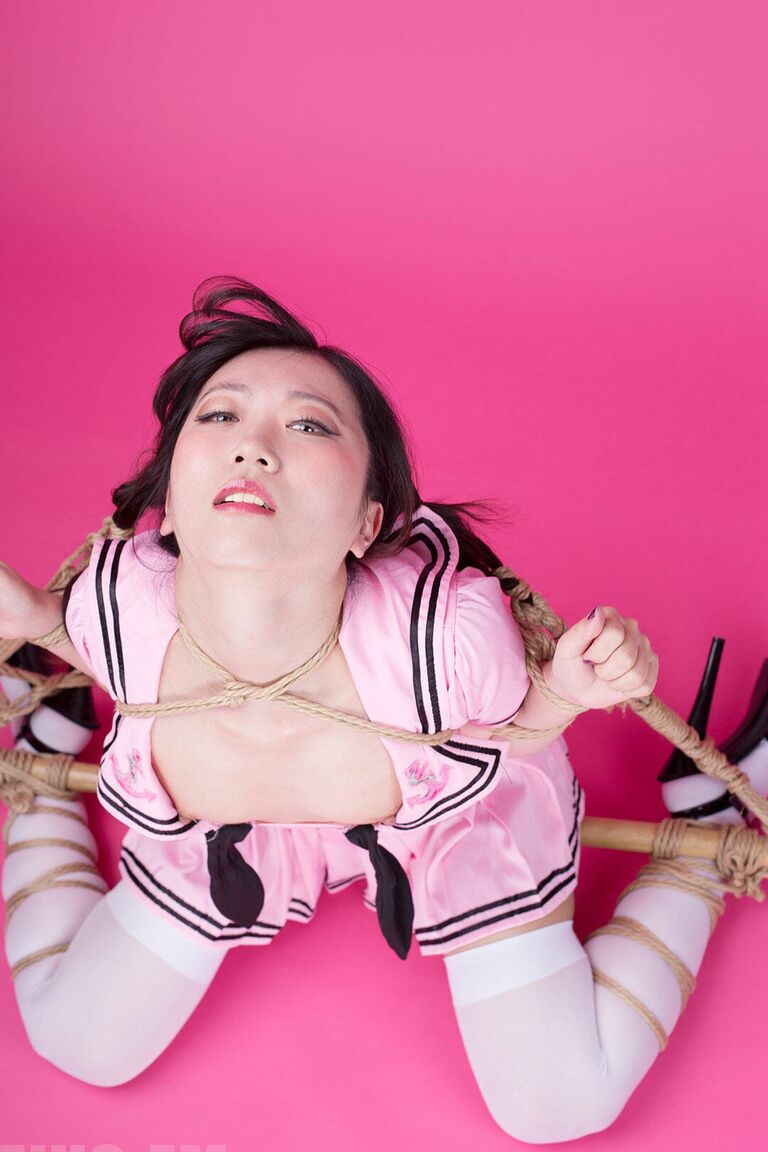 16P, Coco, une fille solo asiatique, tient un parasol après avoir été ligotée et bâillonnée.