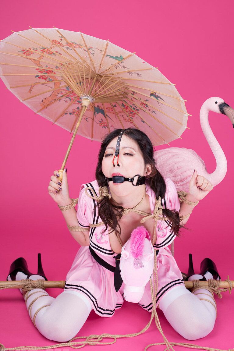 16P, Coco, une fille solo asiatique, tient un parasol après avoir été ligotée et bâillonnée.