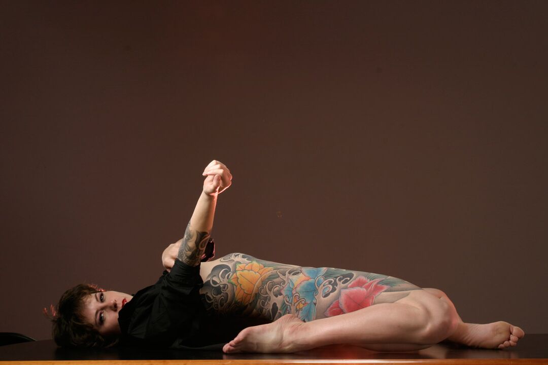 15P La mujer tatuada Michelle Aston realiza estupendas poses semidesnudas sobre una mesa
