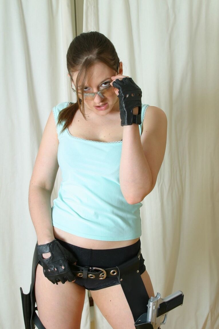 21P Clothed babe in glasses Becky Speed shows her curves while posing with a gun