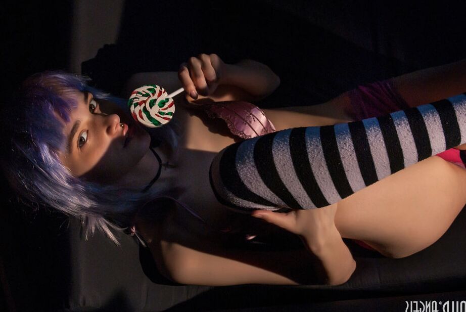 20P Chica adolescente sola con el pelo teñido y piercings muestra sus tetas mientras lame un caramelo