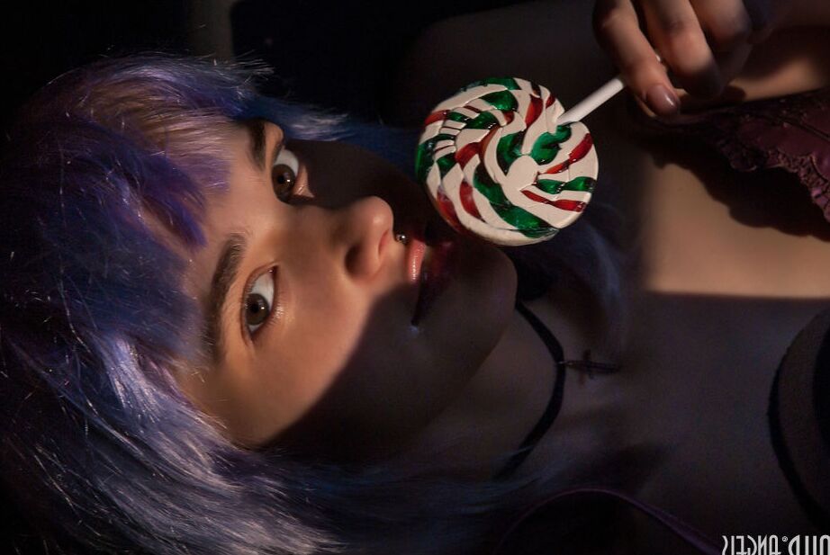 20P Chica adolescente sola con el pelo teñido y piercings muestra sus tetas mientras lame un caramelo