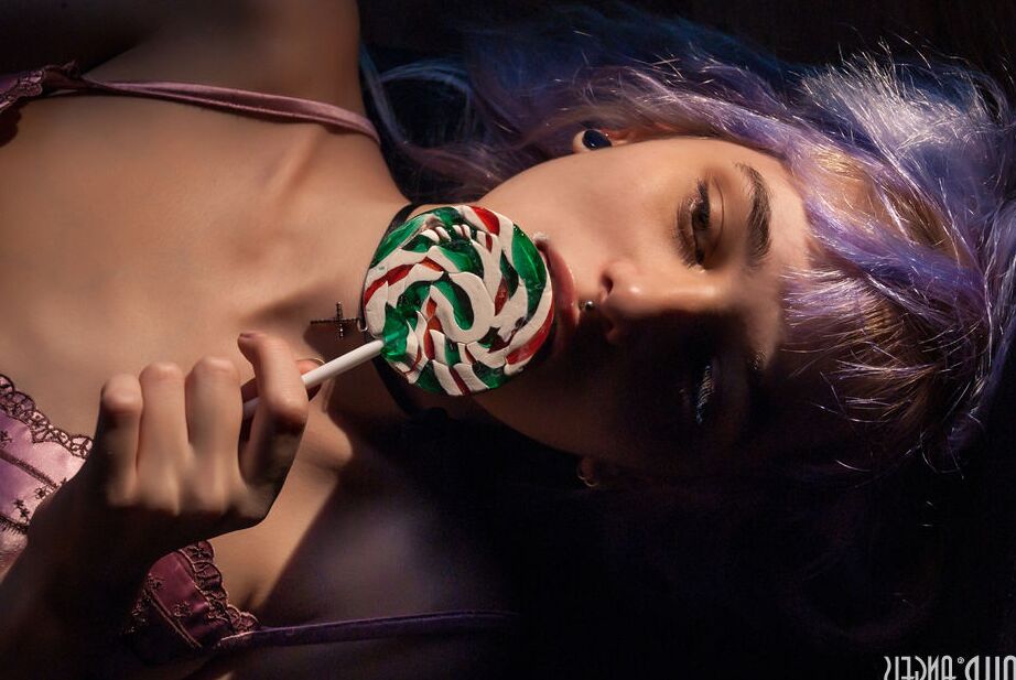 20P Chica adolescente sola con el pelo teñido y piercings muestra sus tetas mientras lame un caramelo