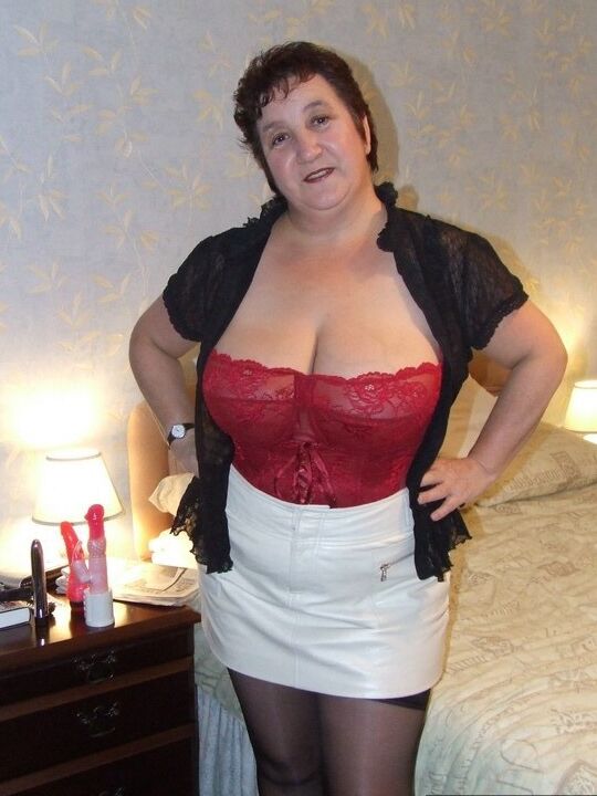 20P Chubby older lady Kinky Carol slips a miniskirt over her thong clad butt