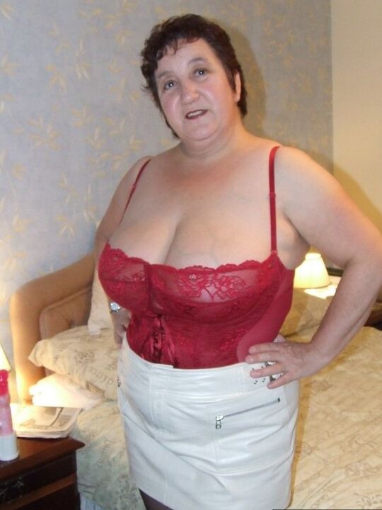 20P Chubby older lady Kinky Carol slips a miniskirt over her thong clad butt
