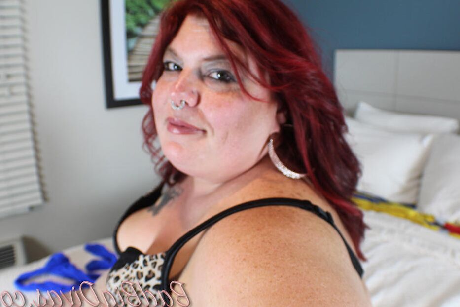 11P Redhead SSBBW Nikki Cakes models a bodystocking in her bedroom