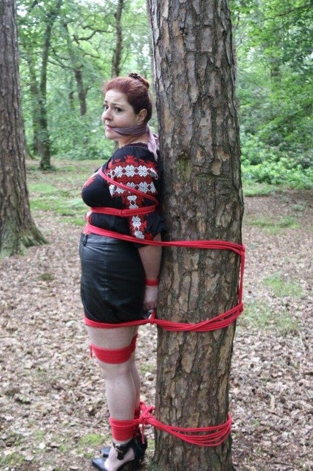 16P Thick redhead is cleave gagged and tied to a tree in a forest
