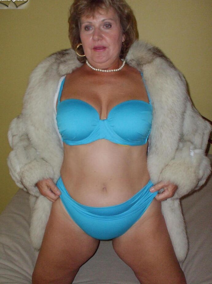20P Mulher mais velha Busty Bliss lambe os lábios antes de mostrar os seios em um casaco de pele
