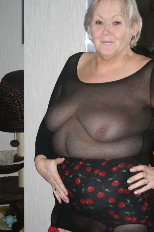 20P Mulher idosa modela suas novas meias vermelhas com roupas transparentes e salto alto