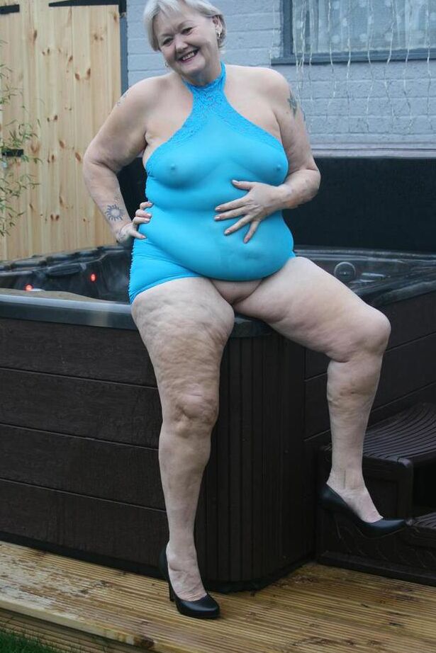 20P Abuela gorda se levanta un vestido transparente para exponer su vagina con zapatos de tacón negros
