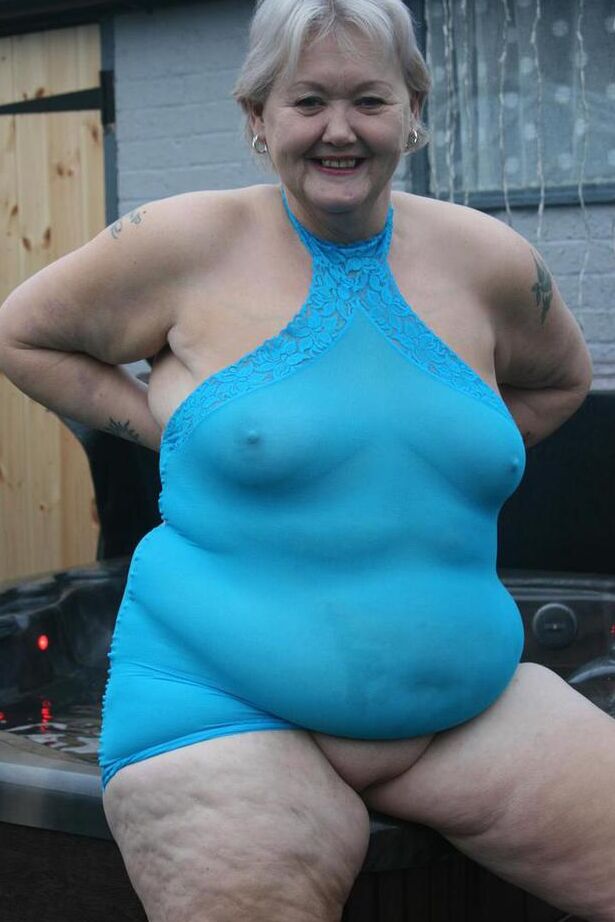 20P Abuela gorda se levanta un vestido transparente para exponer su vagina con zapatos de tacón negros