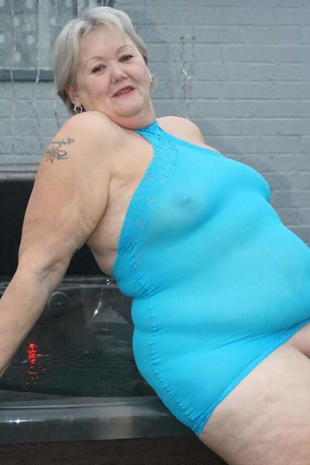20P Abuela gorda se levanta un vestido transparente para exponer su vagina con zapatos de tacón negros