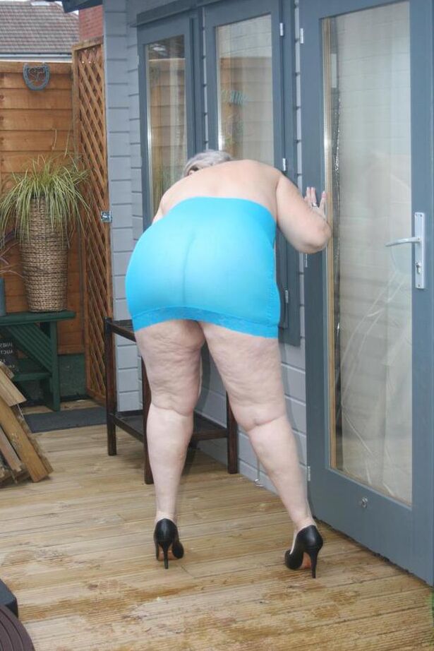 20P Abuela gorda se levanta un vestido transparente para exponer su vagina con zapatos de tacón negros