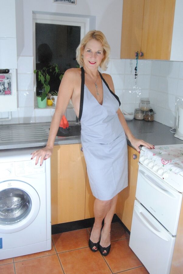 19P Mature MILF with blonde hair wears only an apron while devouring a banana