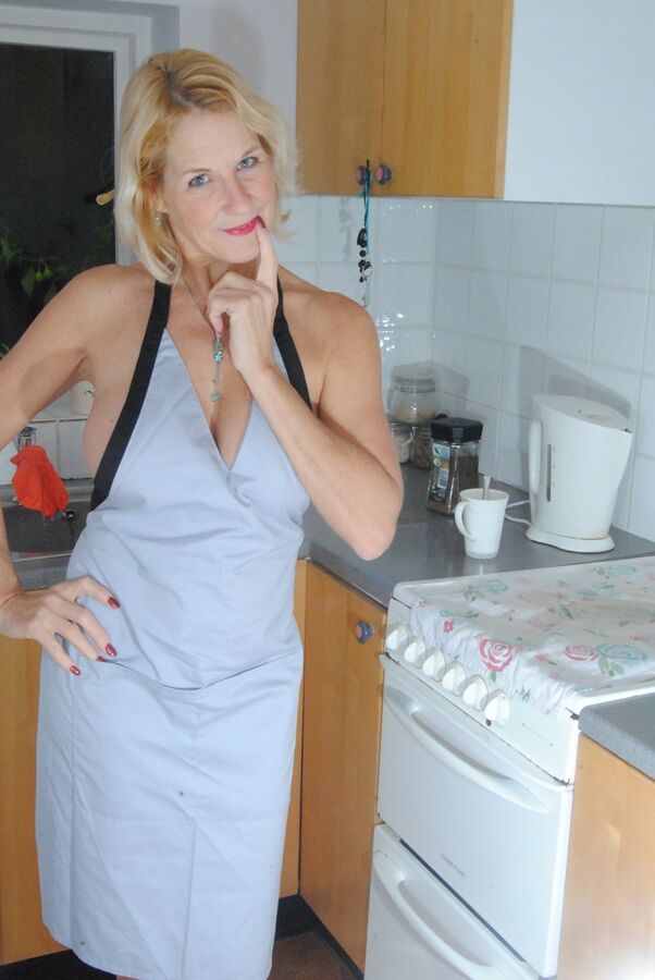 19P Mature MILF with blonde hair wears only an apron while devouring a banana