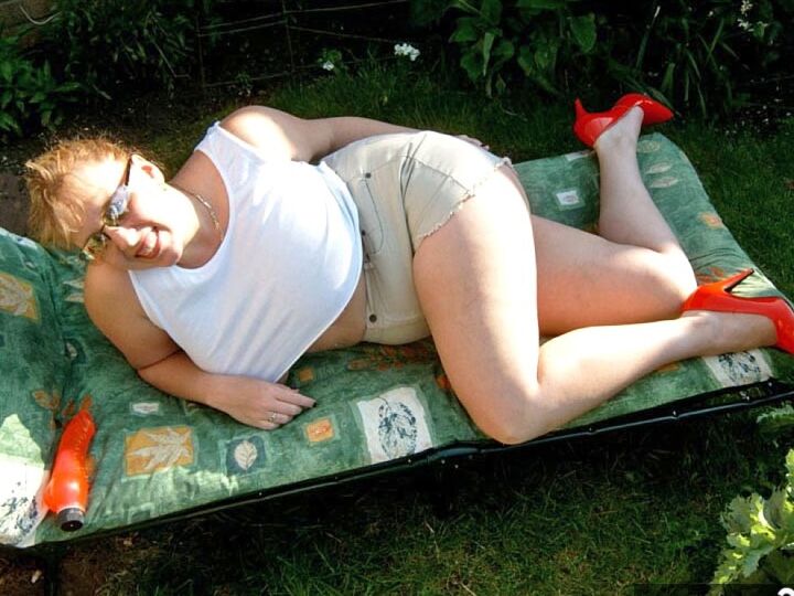 Curvy Claire, amateur britannique de 20P, montre ses seins sur une chaise de jardin tout en suçant un gode.