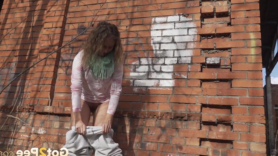 15P Caucasian girl Rita takes a badly needed piss behind a derelict brick building