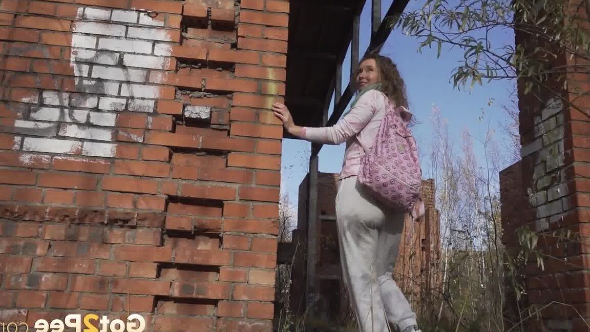 15P Caucasian girl Rita takes a badly needed piss behind a derelict brick building