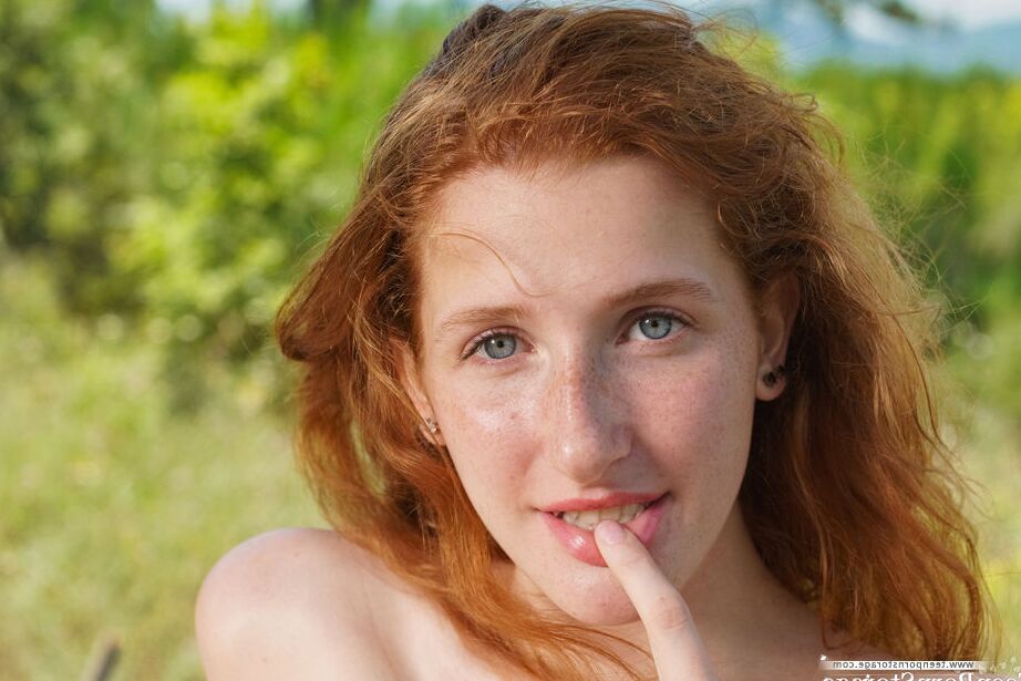 20P Natural redhead Foxy Lee fondles her firm tits and twat on a log in footwear