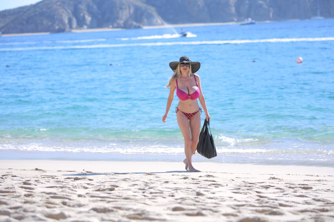 16P La rubia pechugona vestida de rosa Kelly Madison hace alarde de sus curvas en la playa